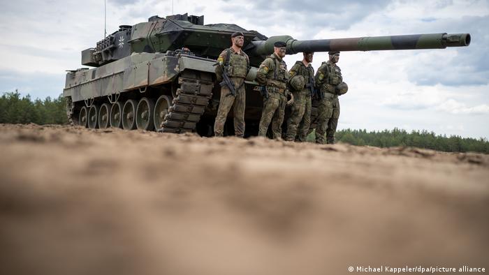  Ein Leopard 2 Panzer, davor vier Soldaten