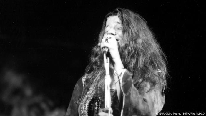 Janis Joplin singt in ein Mikrofon.