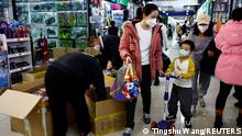11.01.2023
A woman and a child walk past workers sorting toys at a shopping mall in Beijing, China January 11, 2023. REUTERS/Tingshu Wang