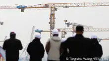 12.01.2023
People look on near cranes standing at a construction site in Beijing, China January 12, 2023. REUTERS/Tingshu Wang