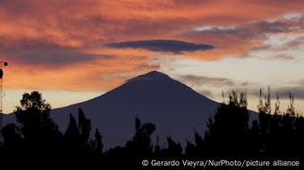 Bajo un cielo rojo de atardecer se ve la silueta negra del Popocatépetl. 