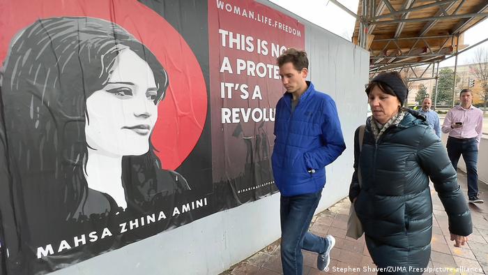 Menschen in den USA gehen an einem Plakat mit dem Porträt von Jina Mahsa Amini vorbei