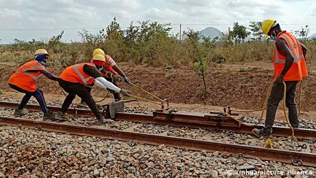 Vier Mitarbeiter in Warnwesten arbeiten an Tansanias Gleisen