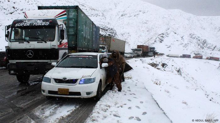 Im Schnee stehengebliebener PKW und LKWs an der pakistanisch-afghanischen Grenze