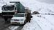 People try to push their vehicle along though a snow-covered road s