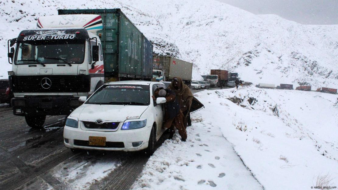 People try to push their vehicle along though a snow-covered road s