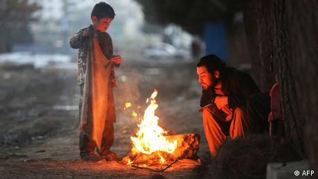 Ein Mann und ein Kind wärmen sich an einem Feuer in einer Straße in Kabul. (Quelle: AFP)