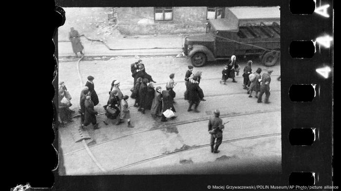un grupo de judíos, hombres, mujeres y niños, es escoltado por soldados alemanes armados hacia Umschlagplatz, lugar desde donde partían hacia los campos de exterminio. 