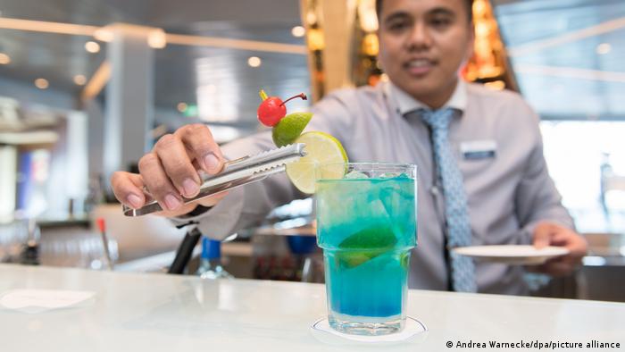Ein Barkeeper mixt einen blauen Cocktail auf einem Kreuzfahrtschiff.