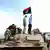 'Befreite' Libyer stehen auf einem Panzer und schwenken eine Flagge aus der Zeit vor Gaddafi (Foto:ap)