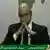 Seif al-Islam, son of Moammar Gadhafi, sits with hands pressed together giving an address on Libyan state television
