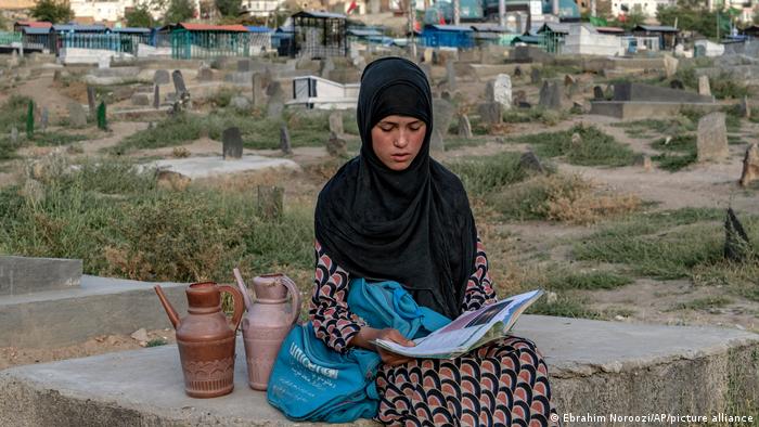 Lesende 14-jährige afghanische Wasserverkäuferin auf einem Kabuler Friedhof