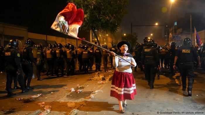 Una mujer protesta junto a agentes policiales en Perú.