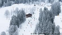 Wintersportler fahren mit einem Skilift eine Skipiste hinauf.