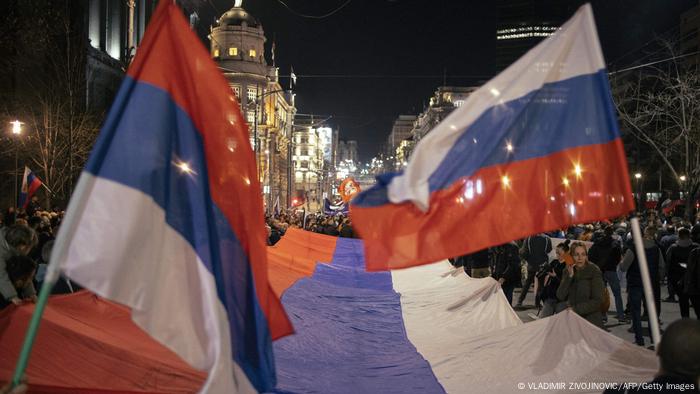 Auf einer Demonstration schwenken Menschen russische Fahnen und tragen eine mehrere Meter große Flagge Russlands durch die Straßen der serbischen Hauptstadt Belgrad