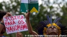 Indigenous leader Nando Potiguara raises a copy of the Brazilian Constitution during a protest against miners working on Yanomami Indigenous land, outside the National Indigenous Foundation in Brasilia, Brazil, Friday, May 6, 2022. The sign reads in Portuguese Justice for the Yanomami.(AP Photo/Eraldo Peres)
