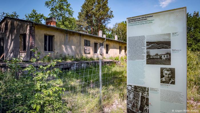 Eine verfallene, steinerne Baracke des als Klinkerwerk bezeichneten Außerlagers, das zum KZ Sachsenhausen gehörte, ist von einem Maschendrahtzaun umgeben. Auf einer Tafel wird über die Funktion dieses Arbeitslagers und das Schicksal der KZ-Häftlinge informiert.