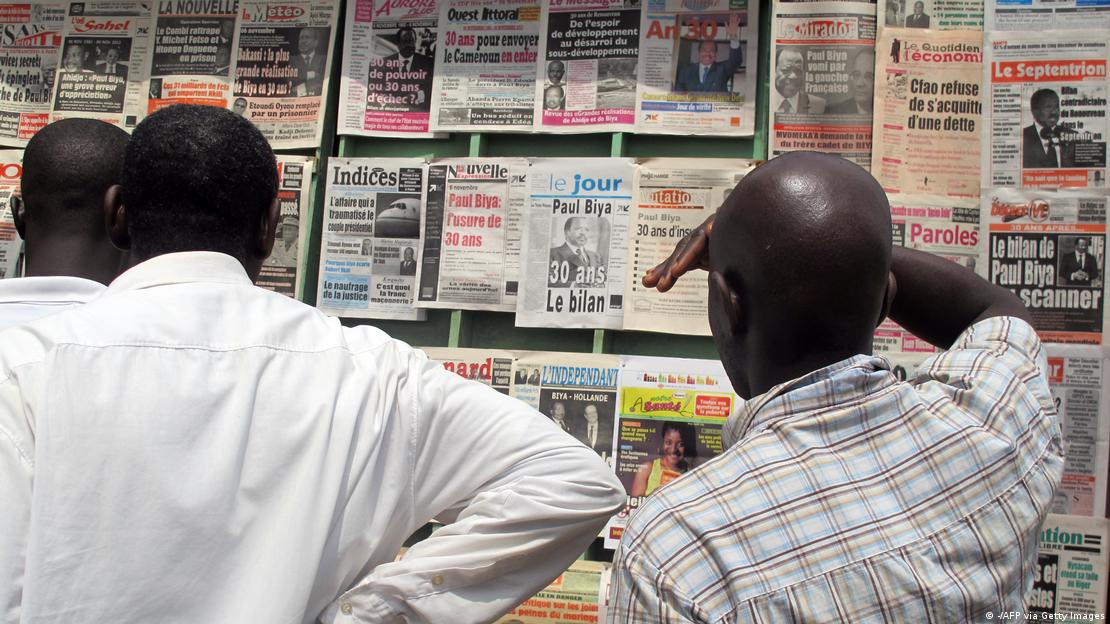 Des Camerounais devant un marchand de journaux