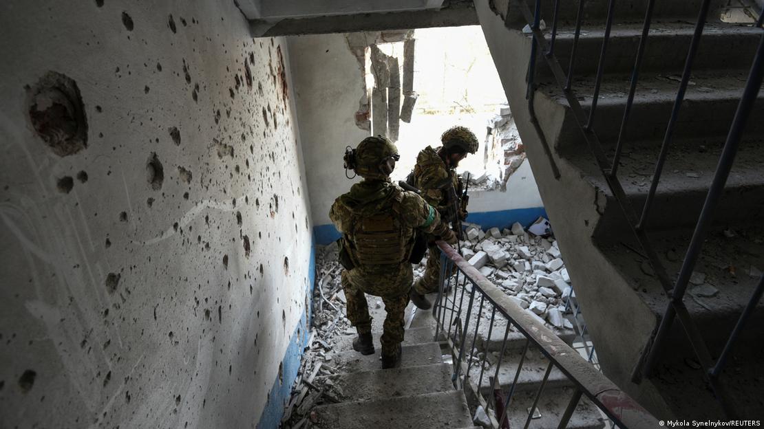 Dois soldados ucranianos inspecionam escadaria destruída de um edifício em Bakhmut, no leste ucraniano