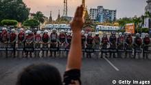 YANGON, MYANMAR - FEBRUARY 06: A protester makes a three-finger salute in front of a row of riot police, who are holding roses given to them by protesters, on February 06, 2021 in Yangon, Myanmar. Myanmar's military junta on Saturday placed heavy restrictions on internet connections and suspended more social media services, almost a week after a coup in which it detained de-facto leader Aung San Suu Kyi and charged her with an obscure import-export law violation. Fresh protests broke out on Saturday morning in the country's capital as authorities moved to make mass arrests amid growing civil disobedience. (Photo by Getty Images/Getty Images)