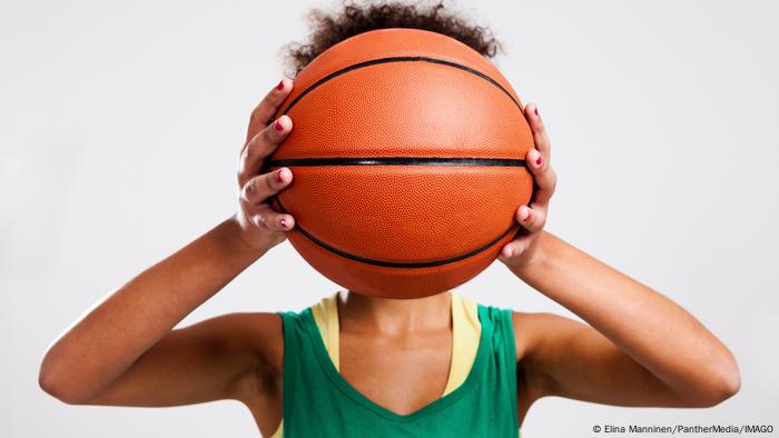 Symbolbild Frau hält sich einen Basketball vor ihr Gesicht