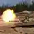 Momento en que un M1A1 Abrams con la enseña estadounidense, apostado entre dos tanques del mismo tipo, dispara.