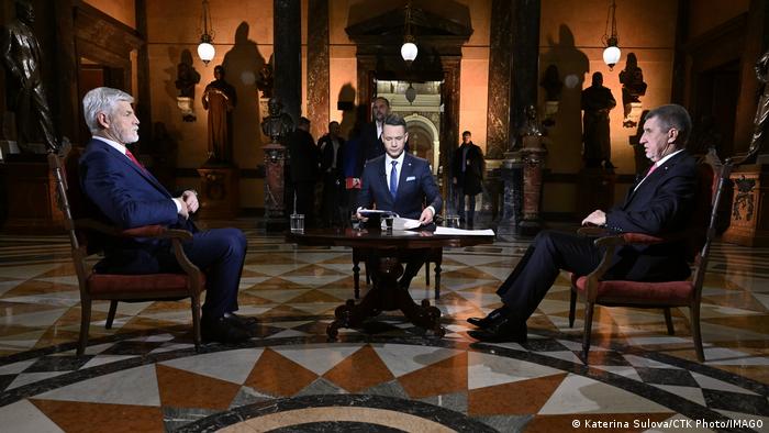​​​​Die beiden Präsidentschaftskandidaten Petr Pavel (l.) und Andrej Babis (r.) sitzen sich beim TV-Duell am 22.0.2023 gegenüber, zwischen ihnen der Moderator an einem Tisch