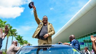 Tundu Lissu standing in an open top car