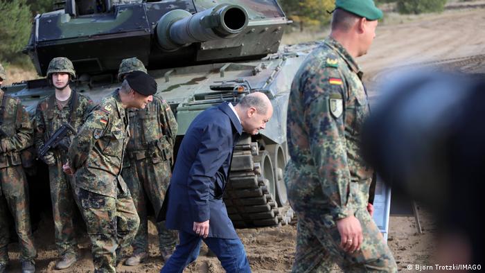 Olaf Scholz baja la cabeza al pasar por debajo de un tanque de combate Leopard 2.