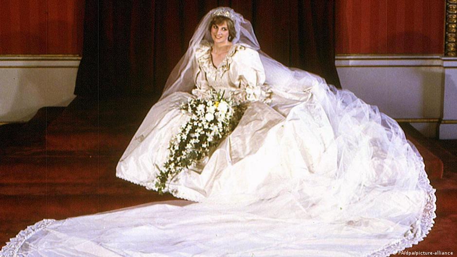 Diana posiert sitzend in einem voluminösen Brautkleid auf einer Treppe, umringt von ihrer Schleppe und einem langen Schleier.