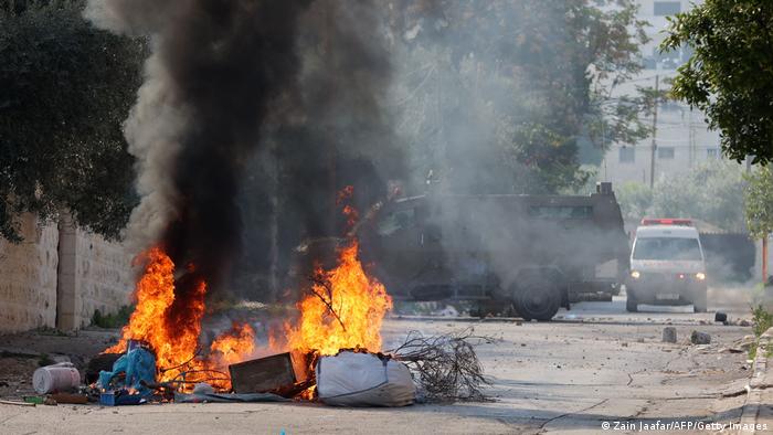Una barricada en llamas cerca de un vehículo militar israelí.