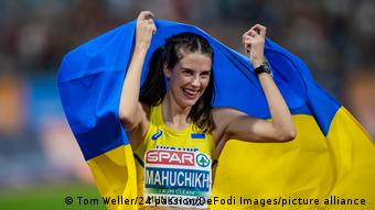 High jumper Yaroslava Mahuchich cheers with the Ukrainian flag at the 2022 European Championships in Munich