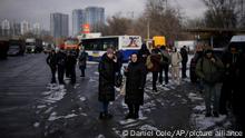 People wait on a street blocked by police after a rocket attack in Kyiv, Ukraine, Thursday, Jan. 26, 2023. (AP Photo/Daniel Cole)