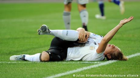 Nationalspielerin Kim Kulig liegt im WM-Viertelfinale 2011 mit geschlossenen Augen am Boden, hält sich das Knie und signalisiert mit der anderen Hand, dass sie ärztliche Hilfe benötigt