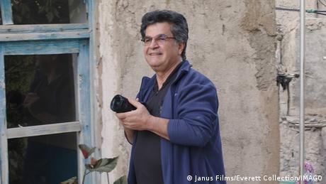 Jafar Panahi mit einem Fotoapparat vor einer Häuserwand.