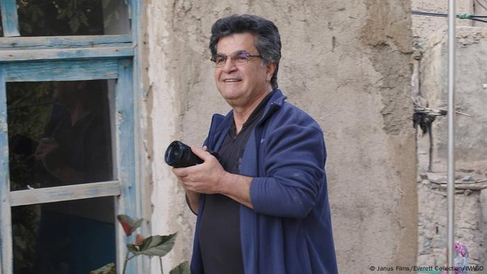 Jafar Panahi mit einem Fotoapparat vor einer Häuserwand.
