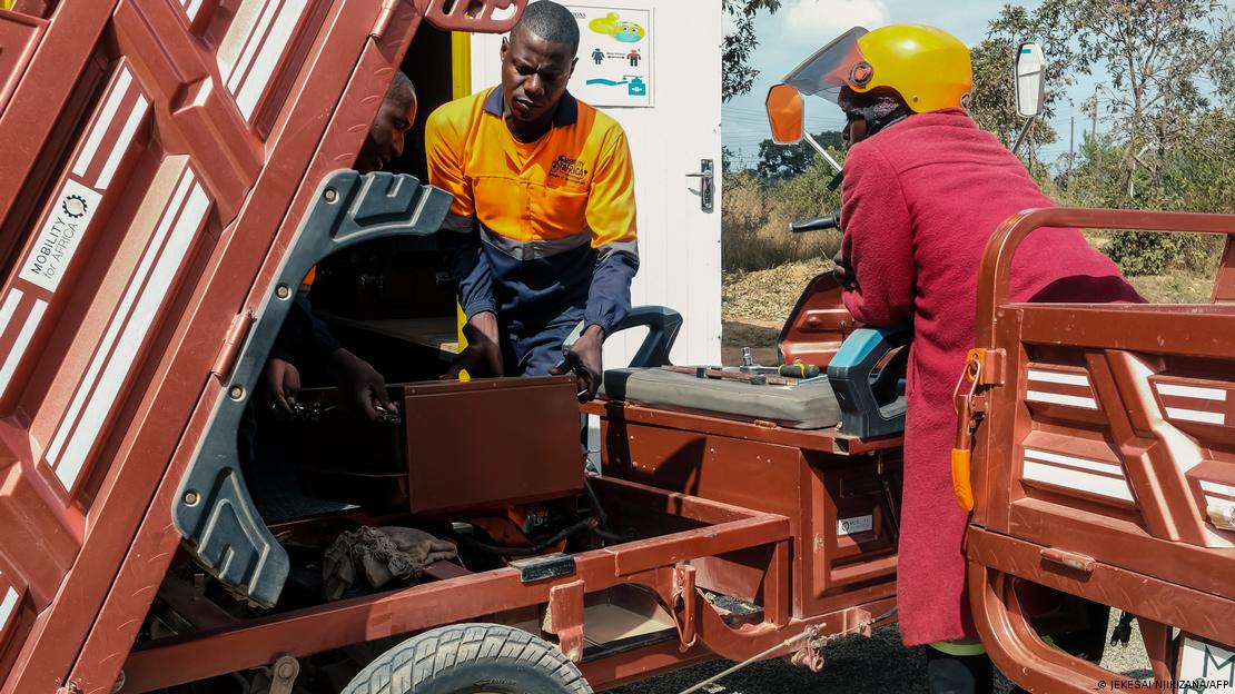 Technicians from Mobility Africa replace a battery pack after a recharge at their solar powered charging hub in Domboshawa into a renewable energy electrical tricycle designed for a rural off road environment