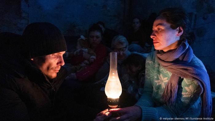 Eine Aufnahmen aus der Dokumentation 20 Tage in Mariupol: Eine Frau und ein Mann halten eine Lampe in der Hand, die Licht ins Dunkel bringt