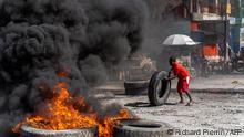 A protestor adds a tire to a burning barricade during a police demonstration to protest the recent killings of six police officers by armed gangs, in Port-au-Prince, Haiti, January 26, 2023. - The attacks, which left six officers dead, occurred on January 25 in the town of Liancourt, when officers had to repel four attacks by the gunmen as they tried to take over the station, according to local news. (Photo by Richard Pierrin / AFP)