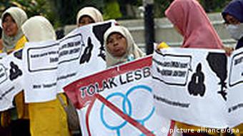 Indonesian muslim students hold their anti-gay and lesbian poster during a protest against the Q! Film Festival in front of the Goethe Institute in Jakarta