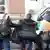 Pamje ilustruese e personave që dëbohen, policë kanë vendosur në mes një djalë veshur me xhup të zi - personat me kurriz nga kamera