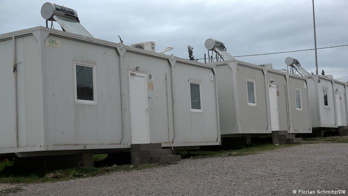 Weiße Wohncontainer stehen in Reih und Glied in einem griechischen Flüchtlingslager