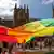 Manifestantes sostienen una bandera arco iris gigante fuera de la Catedral de Santa María antes de la misa de réquiem pontifical por el cardenal George Pell.