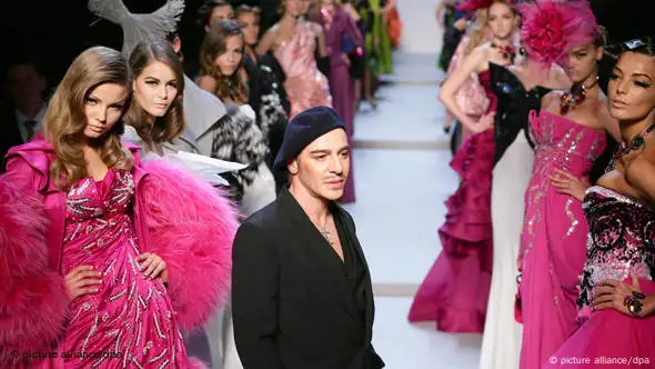 John Galliano bei der Fashionweek in Paris 2008 umringt von Models in pinken Kleidern (Foto: picture-alliance/dpa)