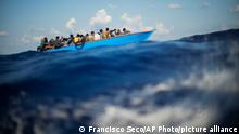 ARCHIV 11.08.2022+++ Migrants in a wooden boat float in the Mediterranean Sea south of the Italian island of Lampedusa on Aug. 11, 2022. (AP Photo/Francisco Seco)