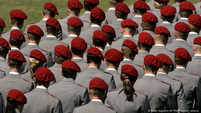 Reihen von Rekruten mit grauen Uniformen und roten Baretten