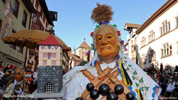 A wooden mask and a traditional costume in a parade.