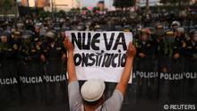 A man holds a banner that reads New Constitution as police officers stand guard during an anti-government protest, following the ouster of Peru's former President Pedro Castillo, in Lima, Peru February 4, 2023. REUTERS/Sebastian Castaneda 