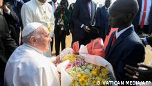 03/02/2023 This handout photo taken and released on February 3, 2023 by the Vatican Media shows Pope Francis (L) receiving a bouquet of flowers from a child as the Pope arrives at the Juba International Airport in Juba, South Sudan. - Pope Francis arrived on a three-day visit to South Sudan on February 3, 2023 to promote peace and reconciliation in the world's youngest country, riven by the scars of civil war and extreme poverty. (Photo by VATICAN MEDIA / AFP) / RESTRICTED TO EDITORIAL USE - MANDATORY CREDIT AFP PHOTO / VATICAN MEDIA - NO MARKETING NO ADVERTISING CAMPAIGNS - DISTRIBUTED AS A SERVICE TO CLIENTS