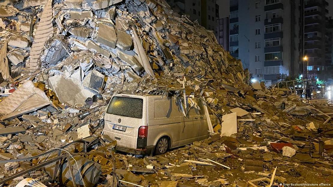 Carros em meio a escombros de prédio que desabou após terremoto na Turquia
